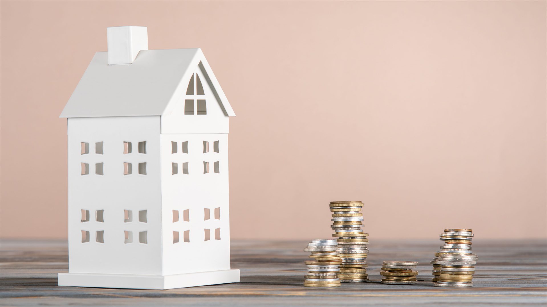 white-toy-model-of-house-with-white-stacks-of-coin