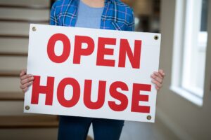 woman-standing-in-the-living-room-holding-open-house-sign